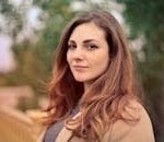 A young woman with long hair smiles confidently for an outdoor portrait session.